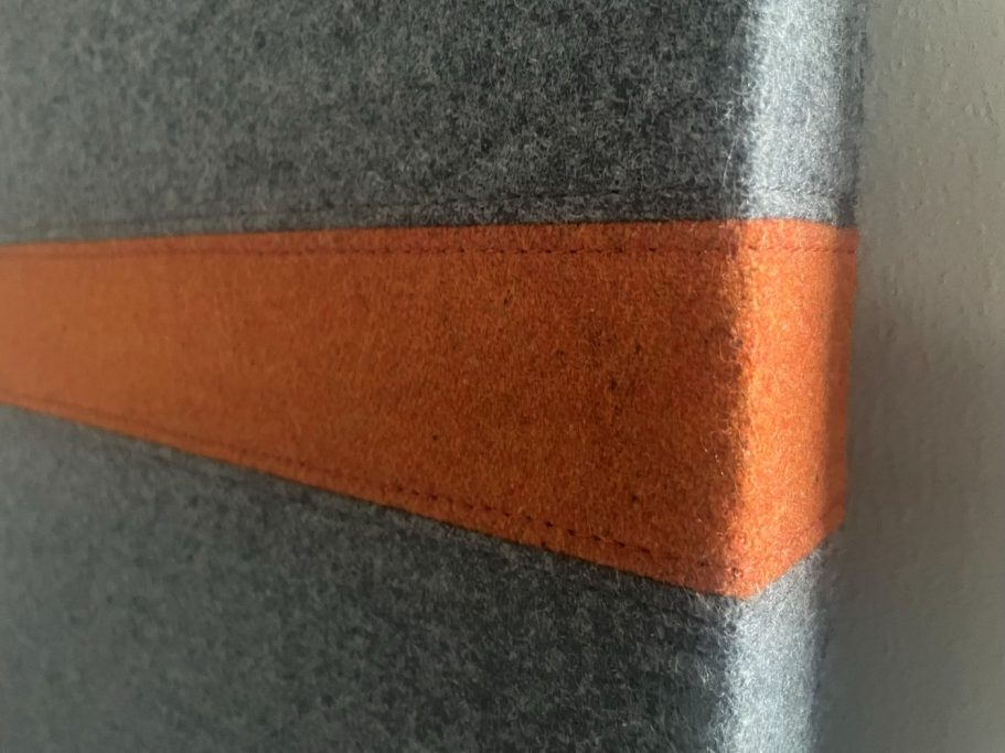 Akustikpaneel von Creation Baumann Grau gefilztes Material mit einer orangefarbenen Naht.